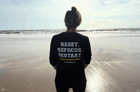 Person wearing Reset Refocus Restart Shirt on Beach Athlete Mindfulness